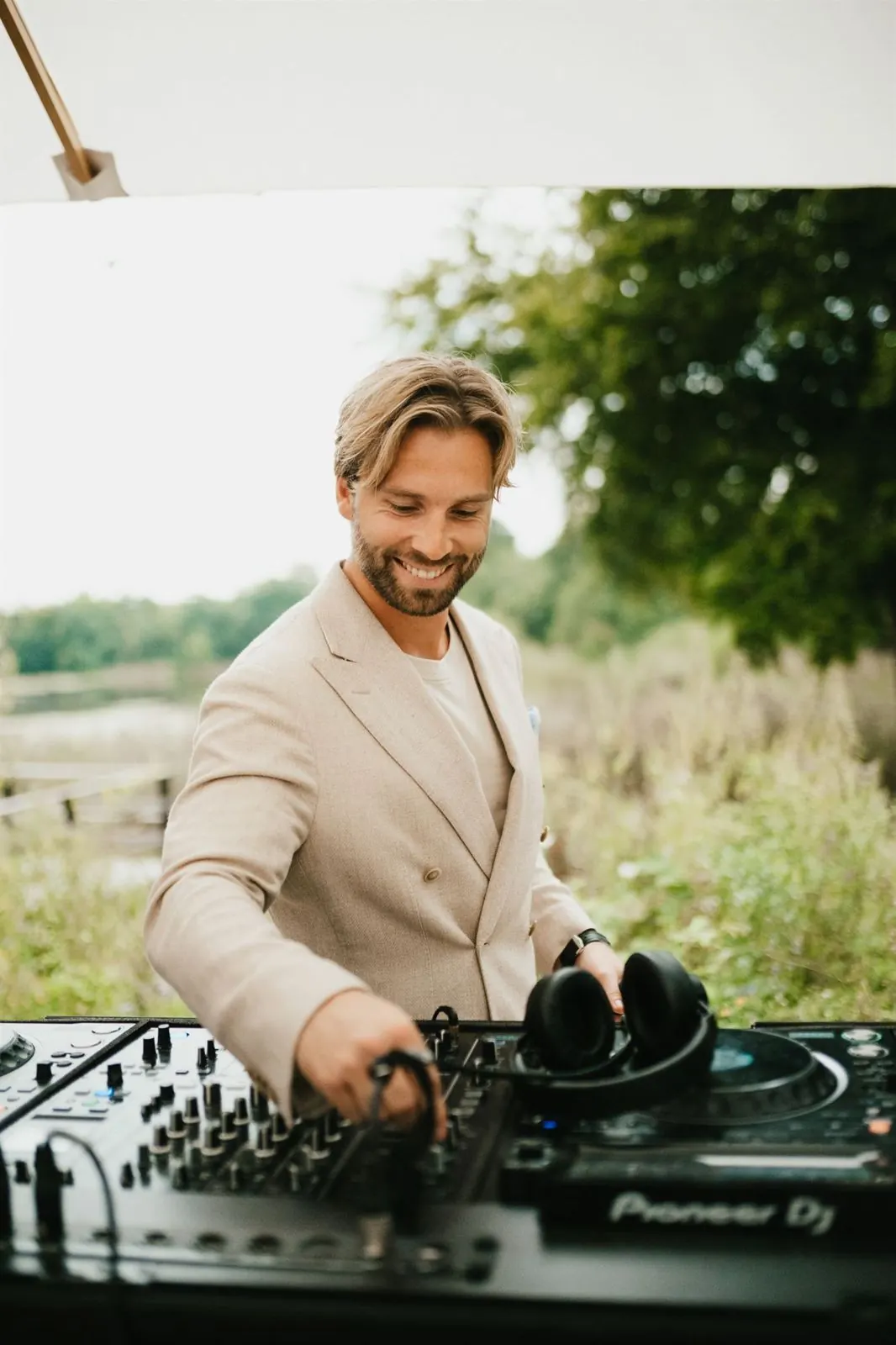 DJ Vejlgaard smiling behind the decks outdoors